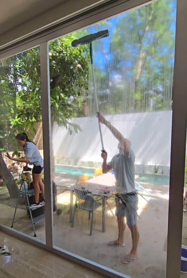 Two Qtana team members cleaning large glass windows together