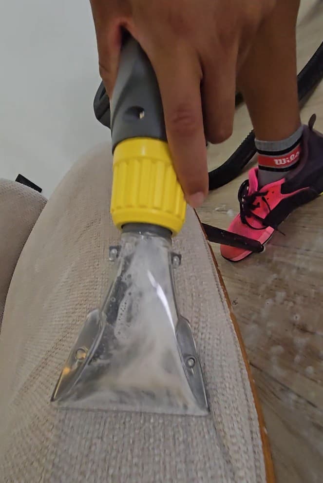 Qtana cleaner using a fabric extraction tool on a couch