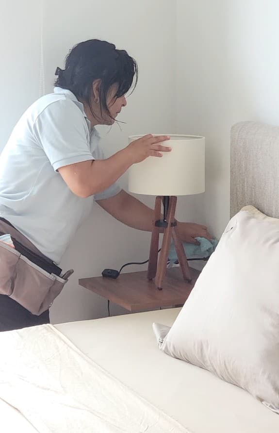Qtana cleaner carefully dusting a bedside lamp